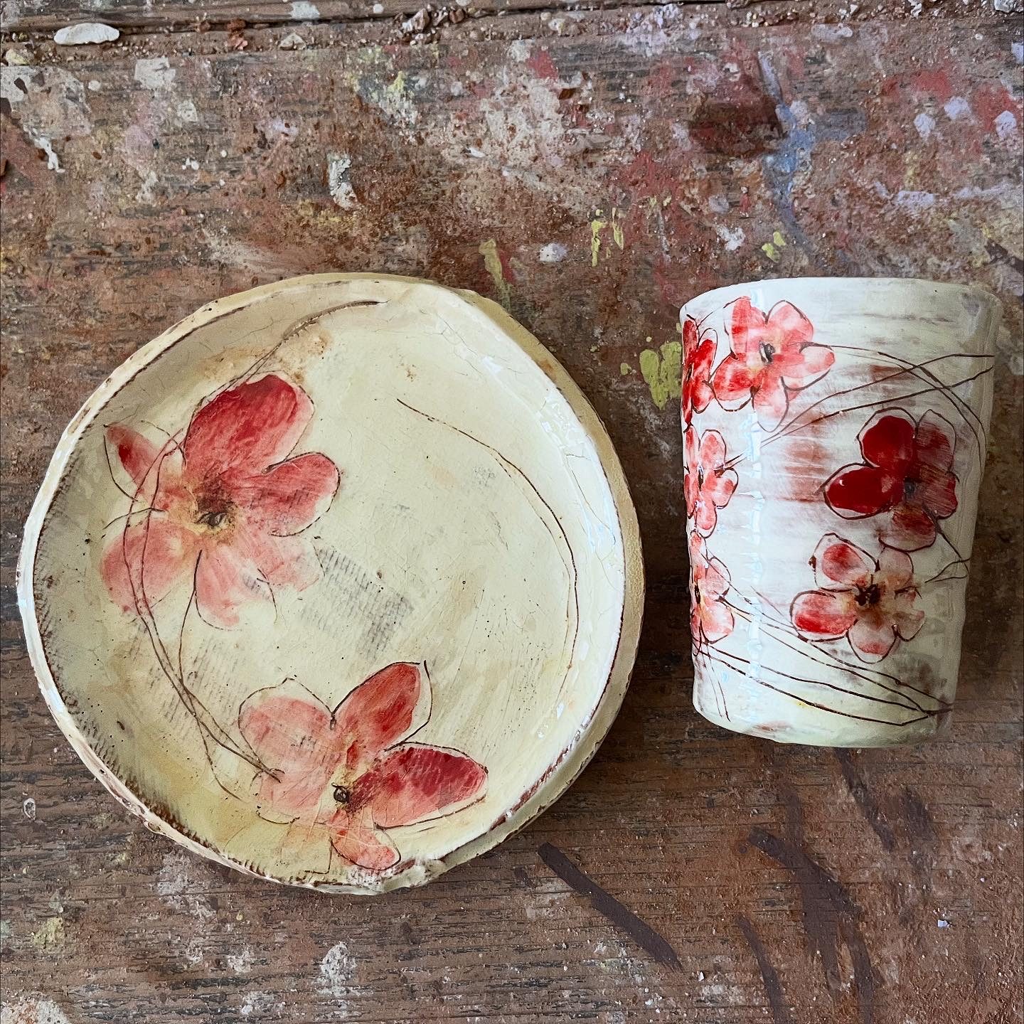 Assiette et tasse en terre cuite émaillée, décor de fleurs rouges sur fond crème, créations de Delphine Mariotti